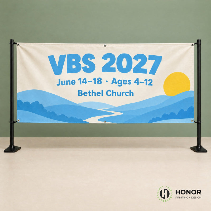 Cream vinyl banner with blue lettering and hills, hung with grommets on a black two-post stand