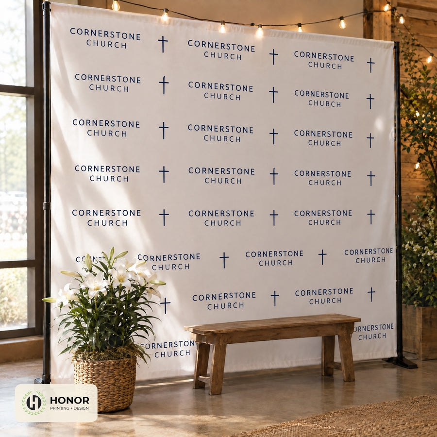 Step-and-repeat backdrop with a bench and plants set up as a photo wall