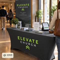 Black stretch table cover at a check-in table beside a retractable banner